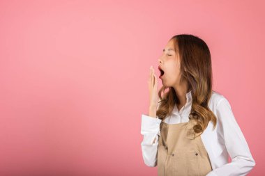 Tulum giymiş güzel bir Asyalı kadın portresi yorgun ve uykulu esneyen ağzı açık, stüdyo resmi pembe arka planda izole edilmiş çekici kadın uykusuzluğu sıkıcı.