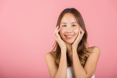 Kadınlık. Asyalı güzel, genç bir kadın gülümseyen kozmetik bantlar gözlerinin altına jel, portre kadın temiz cilde dokunuyor yüzüne tıbbi hidrojel göz bandı, pembe arka planda izole edilmiş, cilt bakımı.