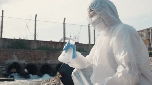 生態学者のサンプリング水毒性化学物質川から試験管ガラスと白い煙があり 生物学者は保護スーツとマスクを着用産業 問題環境からサンプル廃棄物水を収集します — ストック動画