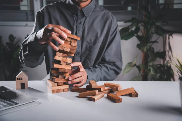 Business fail danger building tower challenge game building. Businessman hand pulling out wood block and failed the tower is falling down he wrong strategy decision