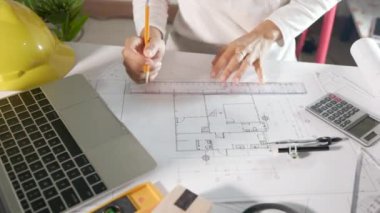 Mimari proje işyeri. Mimarlık bürosundaki masa başı masa üzerinde cetvel üzerinde cetvel çizmeden ya da taslak çizmeden önce evin tasarımını gözden geçirmek için dizüstü bilgisayar klavyesi yazmayı seçin