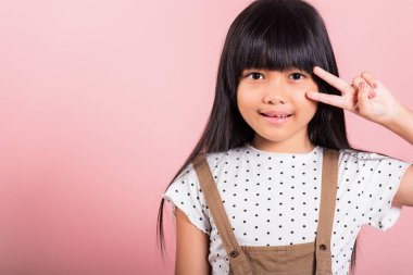 Asyalı küçük bir çocuk. 10 yaşında. Stüdyoda parmak hareketi yapıyor. Pembe arka planda izole edilmiş bir şekilde çekiliyor.