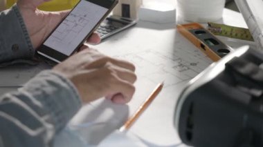 Mimar işyeri. Mimari bina tasarımı ve proje planları, kağıt planları, akıllı cep telefonu ekranı tarafından çevrimiçi insan düzenleme veya mimari denetimi tasarlanması