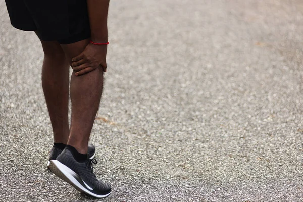 亚洲的年轻运动员运动健将黑衣人站着 穿着脚鞋在户外积极跑步训练 他在跑步时用手抓住膝盖疼痛 运动时运动损伤骨关节炎 — 图库照片