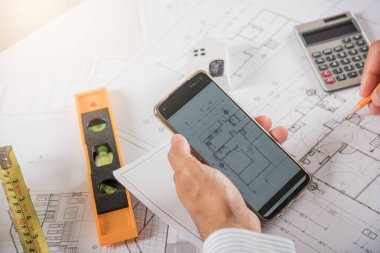 Mimar işyeri. Mimari bina tasarımı ve proje planları, kağıt planları, akıllı cep telefonu ekranı tarafından çevrimiçi insan düzenleme veya mimari denetimi tasarlanması