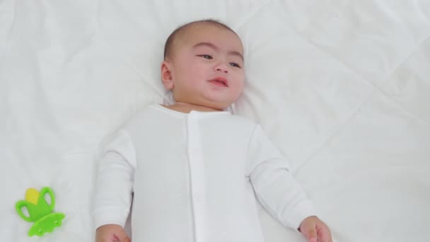 亚洲可爱的小宝宝躺在柔软的毛毯下 身穿紧身衣的宝宝躺在卧室的白床单上 笑着宝宝在家里 — 图库视频影像