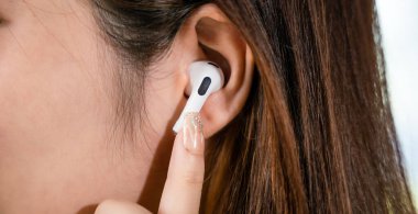 Close up of Happy female touching earbuds to control next listen song on mobile phone in living room at home, Lifestyle woman wearing wireless earphones listening to favorite song on her smartphone