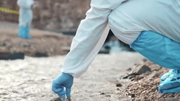생물학자들은 시험관을 사용하여 강에서 추출하고 학자들은 보호용 양복을 마스크를 과학자 — 비디오