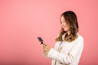 Female surprised and sms chatting internet online on smartphone studio shot isolated on pink background, Happy Asian portrait beautiful cute young woman teen smiling excited hold smart mobile phone