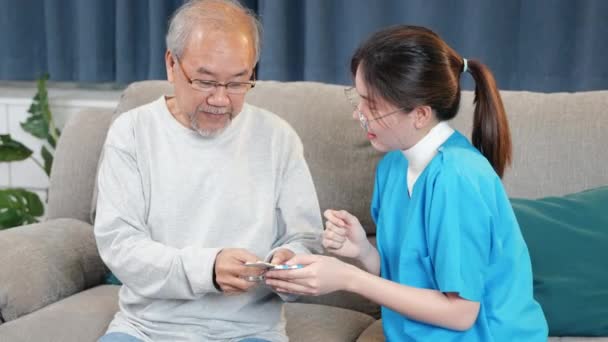 亚洲护士和医生在家里向细心的老人解释处方药 女医生解释剂量药丸老人 医护人员在客厅里拜访病人 — 图库视频影像
