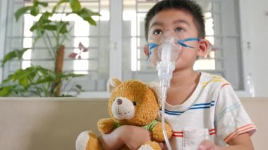 Asian Child using nebulizer mask equipment alone have smoke, Kid boy making makes inhalation nebulizer steam sick cough at home, oxygen spray inhaler therapy, stuffy nose and runny, Health medical