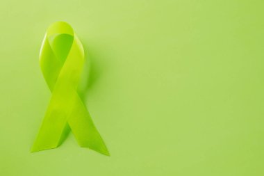 Green awareness ribbon of Gallbladder and Bile Duct Cancer month isolated on green background with copy space, concept of medical and health care support