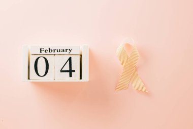 Pink awareness ribbon sign and Calender 4 February of World Cancer Day campaign on pastel pink background with copy space, concept of medical and health care support