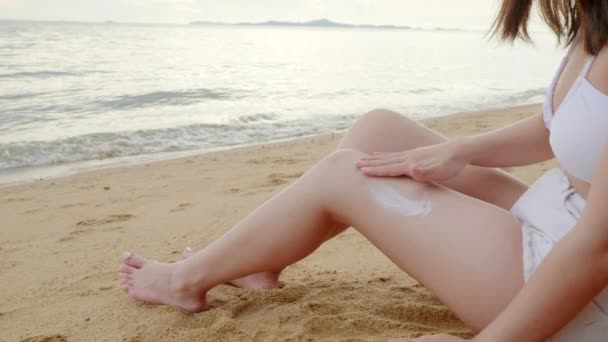 Красивая Азиатская Женщина Наносить Солнцезащитный Крем Загорелые Ноги Тропическом Пляже — стоковое видео