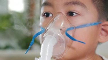 Asian Child using nebulizer mask equipment alone have smoke, Kid boy making makes inhalation nebulizer steam sick cough at home, oxygen spray inhaler therapy, stuffy nose and runny, Health medical