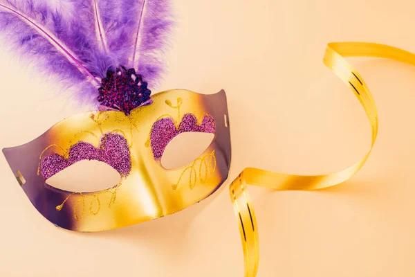 Happy Purim carnival decoration. Top view venetian ball mask with purple feather on pastel background, Jewish Purim and Mardi Gras in Hebrew, holiday background banner design, Masquerade party