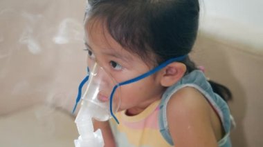 Kid girl making makes inhalation nebulizer steam sick cough at home, Asian Child using nebulizer mask equipment alone have smoke, stuffy nose and runny, oxygen spray inhaler therapy, Health medical