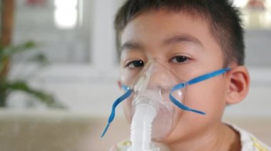 Asian Child using nebulizer mask equipment alone have smoke, Kid boy making makes inhalation nebulizer steam sick cough at home, oxygen spray inhaler therapy, stuffy nose and runny, Health medical