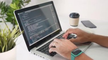Web application development. programmer man writing program code sitting at workplace in office, software developer hands coding HTML programming with laptop computer, IT start up concept, back view