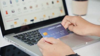 Bilgisayardaki kredi kartlarıyla kadın kaydı elektronik ödeme güvenliğini çevrimiçi yapıyor, kadın eli kredi kartı tutuyor ve evde ürün satın alımıyla dizüstü bilgisayar kullanıyor, internet üzerinden alışveriş kavramı