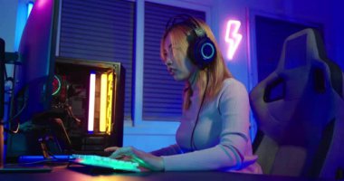 Oyun bitti. Online video oyunu oynayan Asyalı oyuncu bilgisayarında kaybediyor ve üzgün renkli neon ışıklı ışıklar, oyun kulaklığı takan genç kadın kaybedilen oyun için hayal kırıklığına uğruyor, E-Sport konsepti.