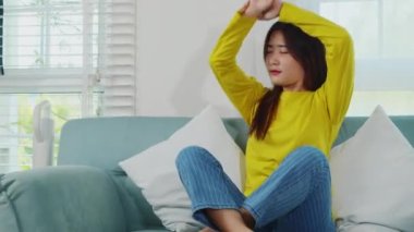Mutlu bir kadın hafta sonu tembellik yapmak, dinlenmek, kanepede dinlenmek, dinlenmek için kendini rahatlatmak için uzanır. Evdeki oturma odasındaki kanepede kollarını uzatan Asyalı genç bir kadın.