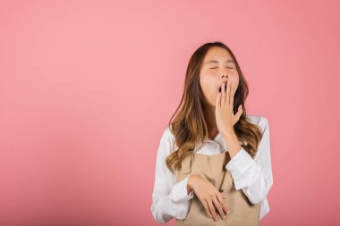 Tulum giymiş güzel bir Asyalı kadın portresi yorgun ve uykulu esneyen ağzı açık, stüdyo resmi pembe arka planda izole edilmiş çekici kadın uykusuzluğu sıkıcı.