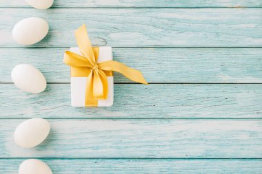 Happy Easter Day. Top view holiday banner background design with easter white eggs and gift box on blue wooden background with copy space