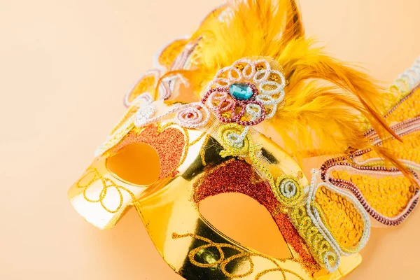 Happy Purim carnival decoration. Close up golden venetian ball mask isolated on pastel background, Jewish Purim or Mardi Gras in Hebrew, holiday background banner design, Masquerade party