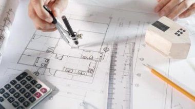 Mimari proje işyeri. İnşaat projesini çizen mühendis, mimarlık bürosundaki masa masasındaki tamir araçları için ev planı taslak kağıdına bölücü pusula çizen mimar.