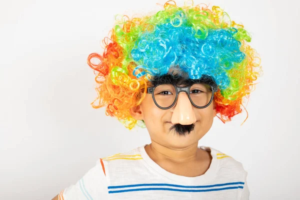 4月の愚か者の日 面白い子供の少年ピエロの肖像画は 大きな鼻と眼鏡をカラフルな巻きウィッグを身に着けており コピースペースと白の背景に隔離された口ひげを持っています 幸せな子供のお祝いの装飾 — ストック写真