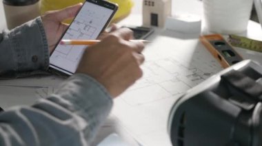 Mimar işyeri. Mimari bina tasarımı ve proje planları, kağıt planları, akıllı cep telefonu ekranı tarafından çevrimiçi insan düzenleme veya mimari denetimi tasarlanması
