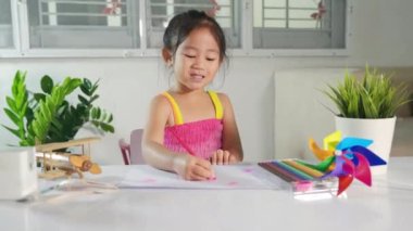 Mutlu çocuk beyaz kağıda pembe kalp çizen küçük kız, gülümseyen Asyalı şirin çocuk anaokulu çocuğu evde renkli resim çek, sevgililer günü ya da anneler günü ya da babalar günü.
