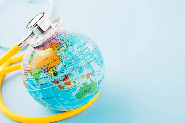 World Health Day. Yellow doctor stethoscope and world globe isolated on blue background, Save world day, Green Earth, Healthcare and medical concept