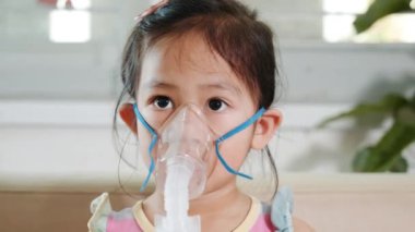 Kid girl making makes inhalation nebulizer steam sick cough at home, Asian Child using nebulizer mask equipment alone have smoke, stuffy nose and runny, oxygen spray inhaler therapy, Health medical