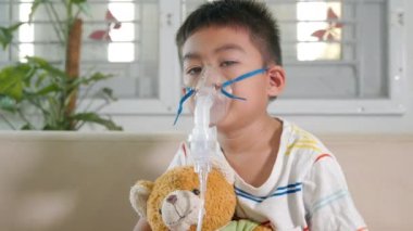 Asian Child using nebulizer mask equipment alone have smoke, Kid boy making makes inhalation nebulizer steam sick cough at home, oxygen spray inhaler therapy, stuffy nose and runny, Health medical