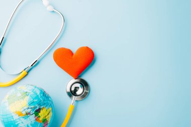 Dünya Sağlık Günü. Sarı doktor stetoskop ve kırmızı kalp şekilli dünya küresi mavi arka planda fotokopi alanı ile izole edilmiş, Dünya 'yı Kurtarma Günü, Sağlık Sigortası, Sağlık ve Tıbbi Konsept