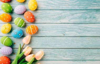 Paskalya Günü Konsepti. Üst görünüm tatil afişi web tasarımı beyaz renkli paskalya yumurtaları mavi ahşap arka planda lale çiçekleri boş fotokopi alanı ve kutlama kartı