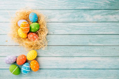 Happy Easter Day Concept. Flat lay of holiday banner background web design easter eggs in brown nest on blue wooden background with empty copy space, celebration greeting card, overhead, template