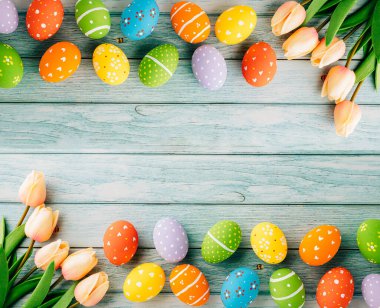 Happy Easter Day Concept. Flat lay holiday banner background web design white colorful easter eggs painted with tulips flowers on blue wood background with empty copy space, overhead, template