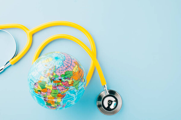 World Health Day. Yellow doctor stethoscope and world globe isolated on blue background, Save world day, Green Earth, Healthcare and medical concept