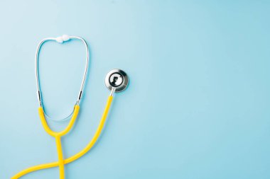Yellow medical stethoscope isolated on blue background with copy space for you text, Doctor equipment, Overcoming the disease, Doctor Day Concept