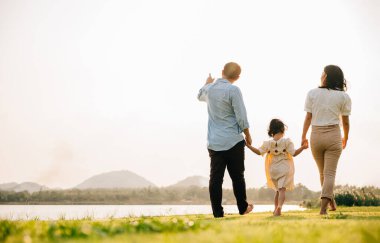 Tayland 'da güzel bir parkta birlikte yürüyen dört kişilik bir aile. Yeşil bir geçmişi ve eğlence ve heyecanı var. Aile günü, arka plan.
