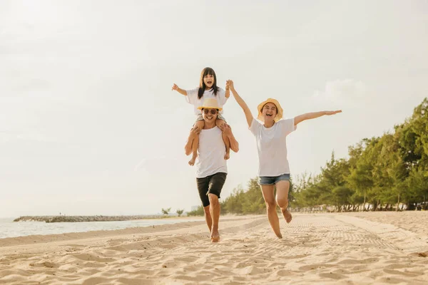 道路の旅の日 ビーチで夏休みを楽しんでいる幸せな家族 砂のビーチでレースをしている父親と母親に乗っている娘 屋外で一緒に遊んでいる道路の家族旅行を楽しむ — ストック写真