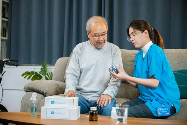 医師が処方薬を説明するアジアの看護師は 自宅で気配りのある高齢者に 医師の女性は 生活室で家の中で訪問薬の老人 医療従事者を説明します — ストック写真