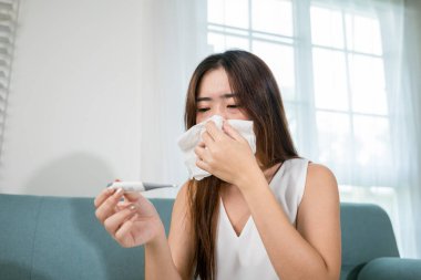 Hasta kadının ateşi var. Evdeki termometreyle ateşini ölçüyor. Grip, ateş, sağlık ve tıbbi konseptten muzdarip genç bir kadın.