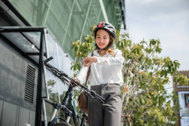 Portre gülümseyen kadın kontrol saati, Asyalı genç iş kadını bisiklet ile duruyor modern binalarda saati kontrol ediyor sabah işe gitmeden önce, iş seyahati, yaşam tarzı