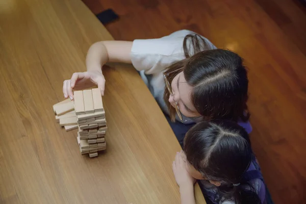 미소짓는 여자는 아이들 블록을 만드는 사람을 가르치는 도움을 주는데 아시아의 — 스톡 사진