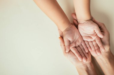 Kapalı eller çocuklar yetişkin anne eli, üst düzey çocuk anne avuç içleri, ebeveynler ve küçük çocuk el ele tutuşuyorlar pastel arka planda izole edilmiş, aile gündüz bakımı konsepti.
