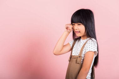 Unhappy children. Asian little kid 10 years old bad mood her cry wipe tears with fingers at studio shot isolated on pink background, child girl stress feeling sad unhappy crying